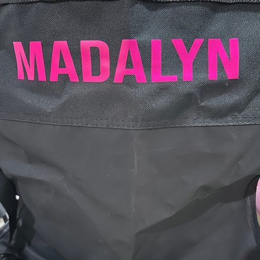 Black chair with 'MADALYN' in pink on the back.