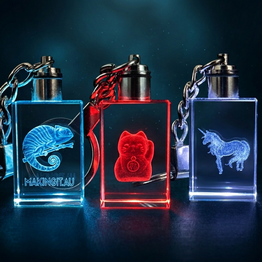 Three illuminated keychains with engraved designs on a dark background