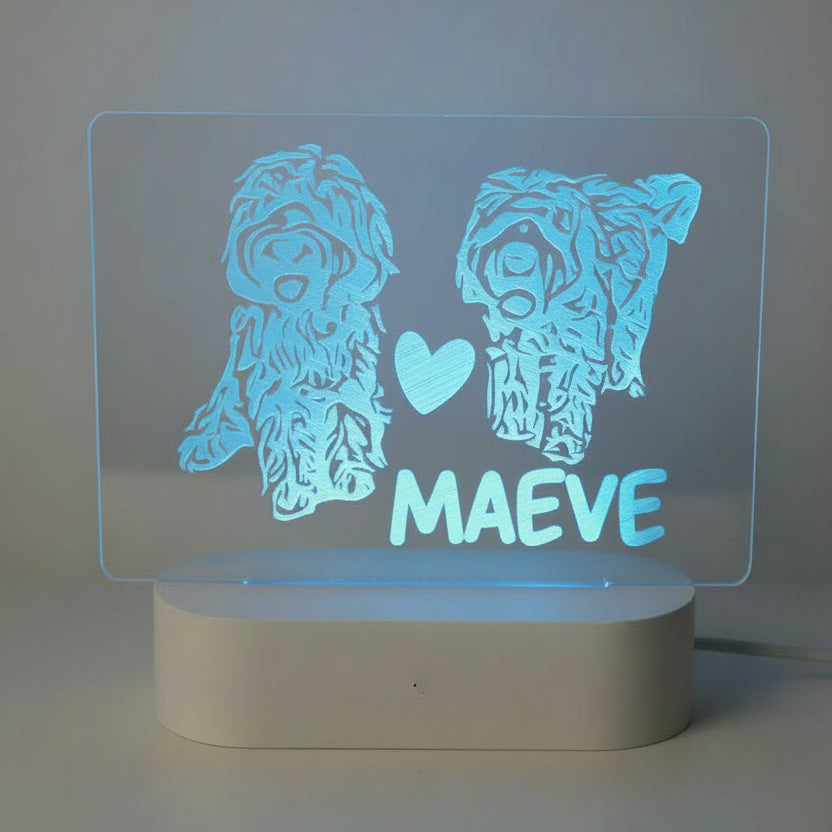 Glowing blue LED sign with two dog illustrations and the name 'Maeve' 