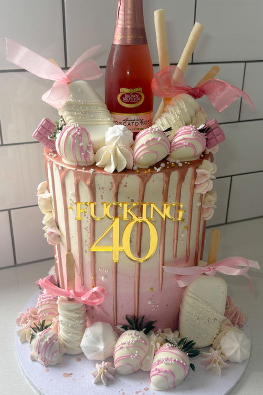 Decorative cake with 'FUCKING 40' text and a bottle on a white tiled background
