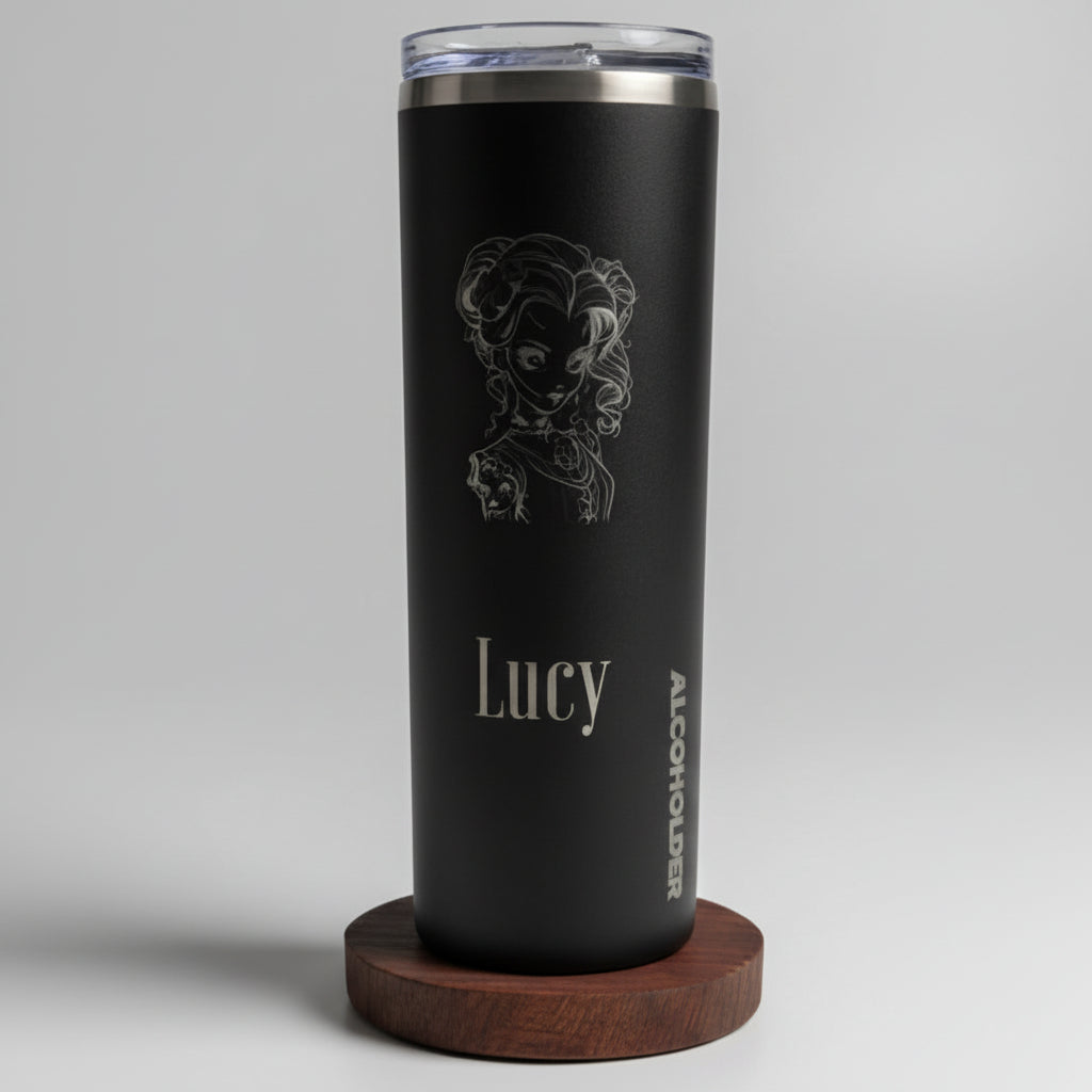 Black tumbler with 'Lucy' engraving next to a SKINZ box on a wooden surface