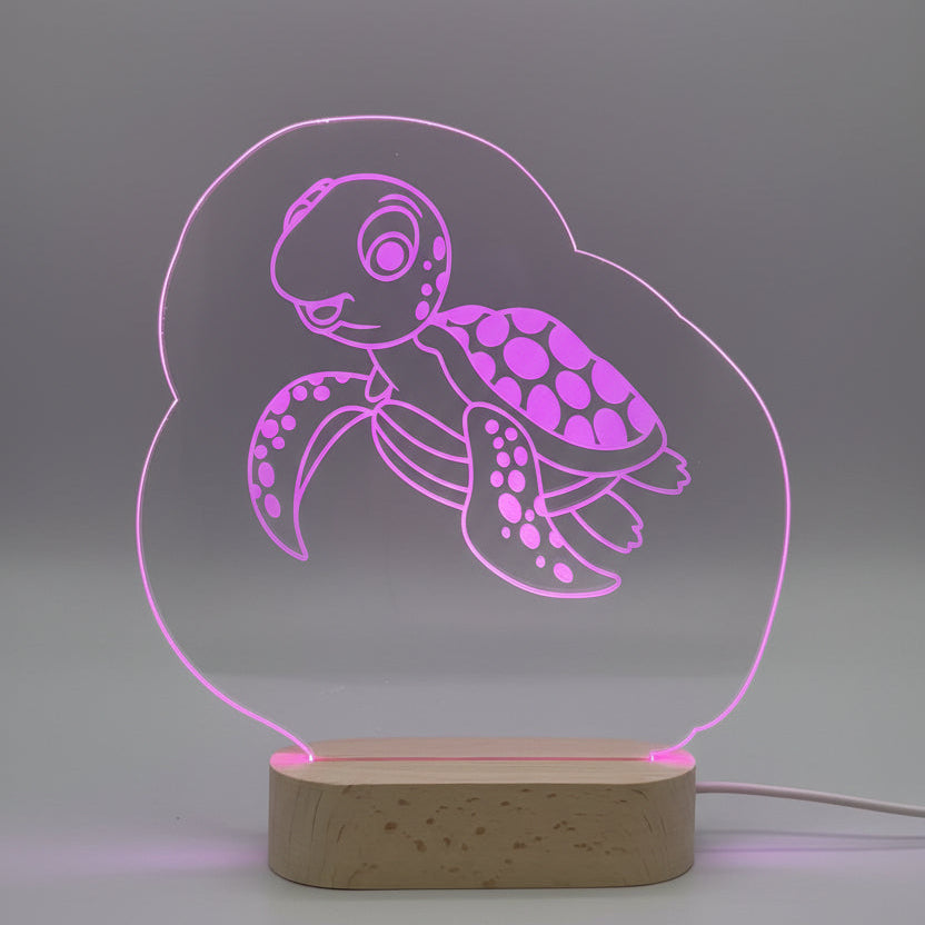 LED lamp with turtle design on a wooden base, glowing pink.