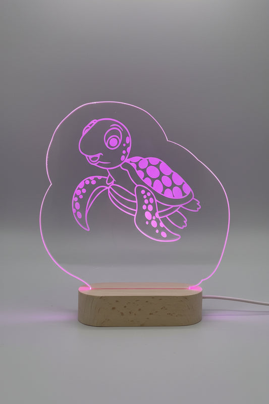 LED lamp with turtle design on a wooden base, glowing pink.