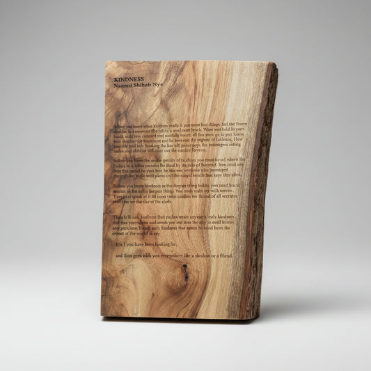 A rustic live-edge wooden plaque featuring engraved text, photographed on a dark surface.