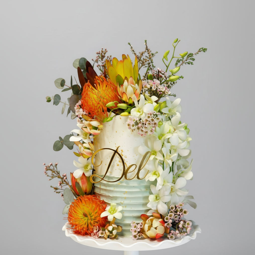 Decorative cake with flowers and 'Del' Gold mirror acrylic cake topper