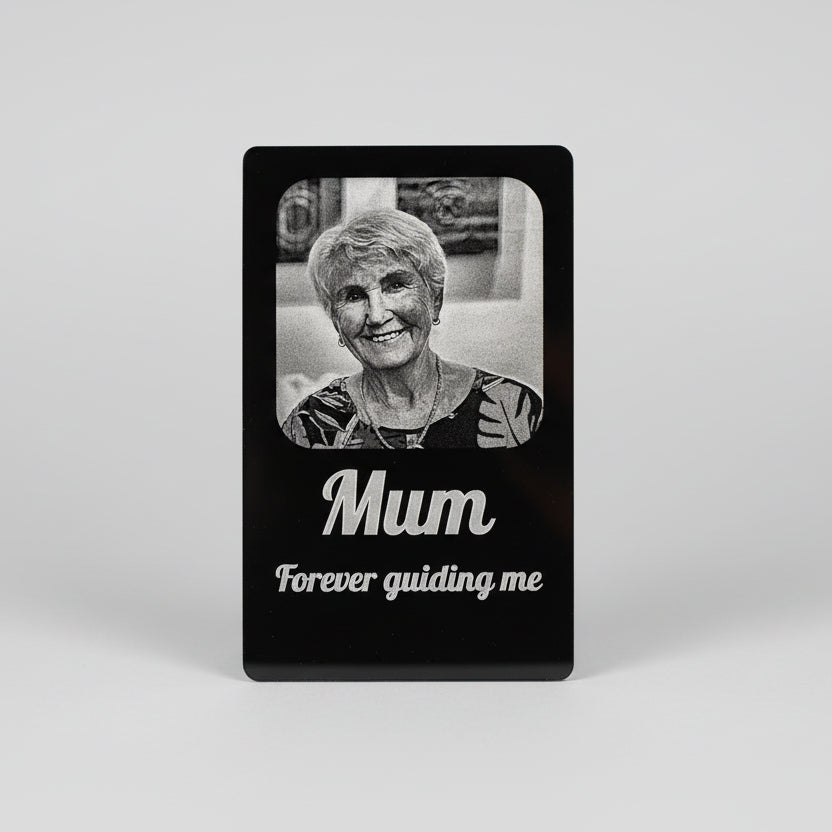 Black card with a photo of an elderly woman and the text 'Mum Forever guiding me' held by a hand.