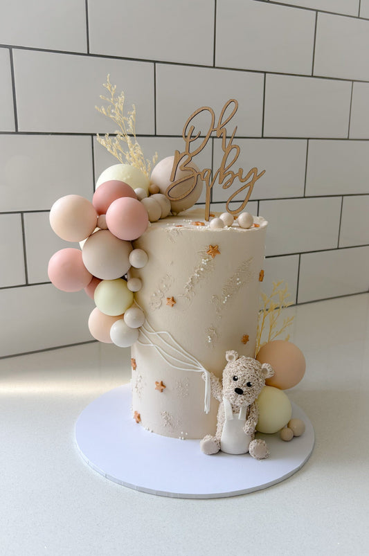Baby shower cake with balloons and 'Oh Baby' Timber Cake topper on a white background
