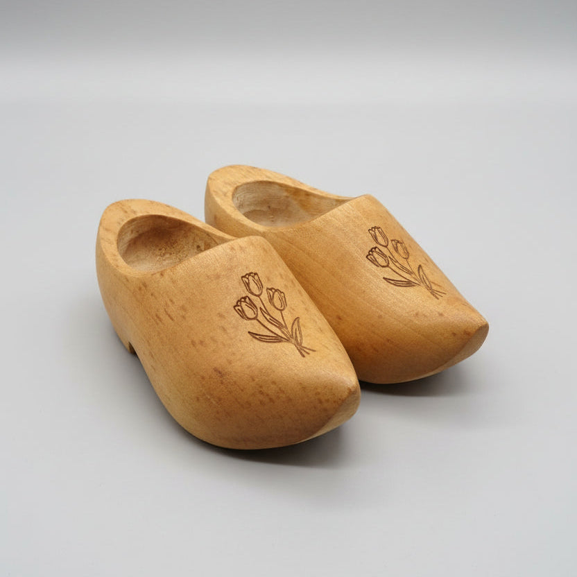 Pair of wooden clogs with tulip design on a white background.