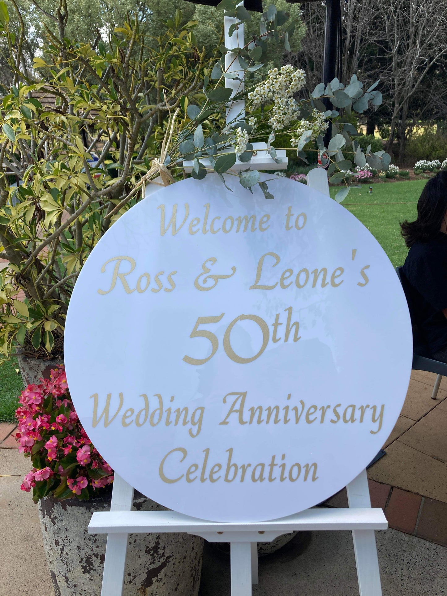 Decorative sign for Ross & Leone's 50th wedding anniversary celebration with floral background.