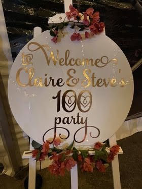 Decorative sign for Claire & Steve's 100th party with floral elements.