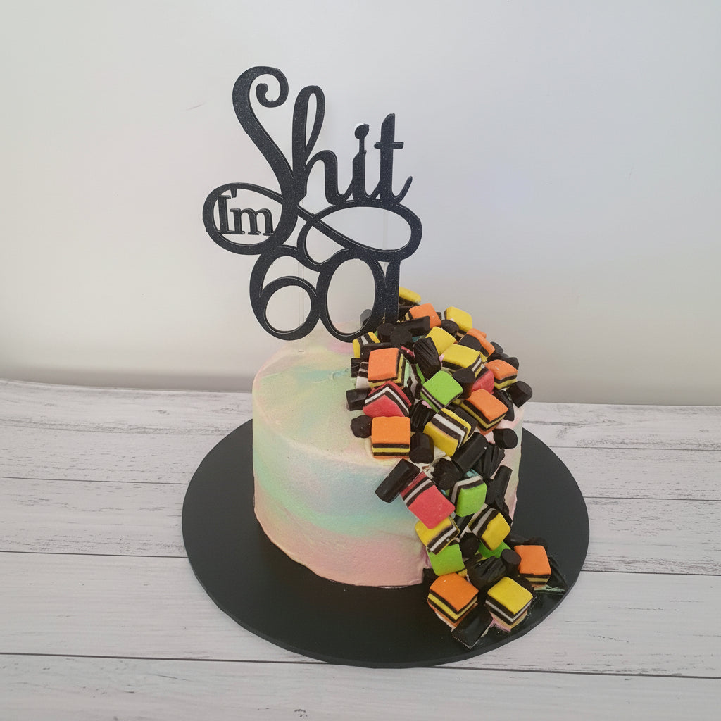 Birthday cake with colorful candy decorations and a black topper on a white background